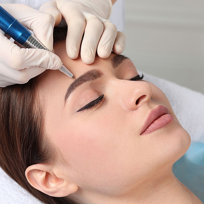 Woman getting eyebrow microblading treatment.