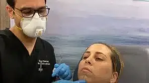 Dermatologist performing treatment on patient’s face.