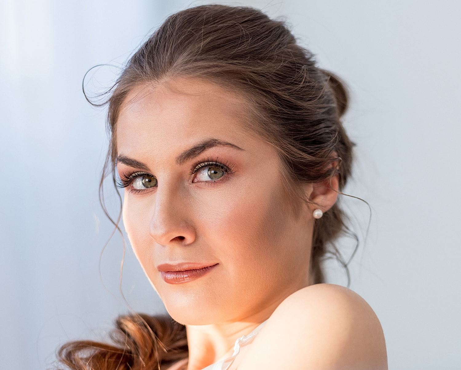 Woman with elegant makeup and hairstyle, softly smiling.
