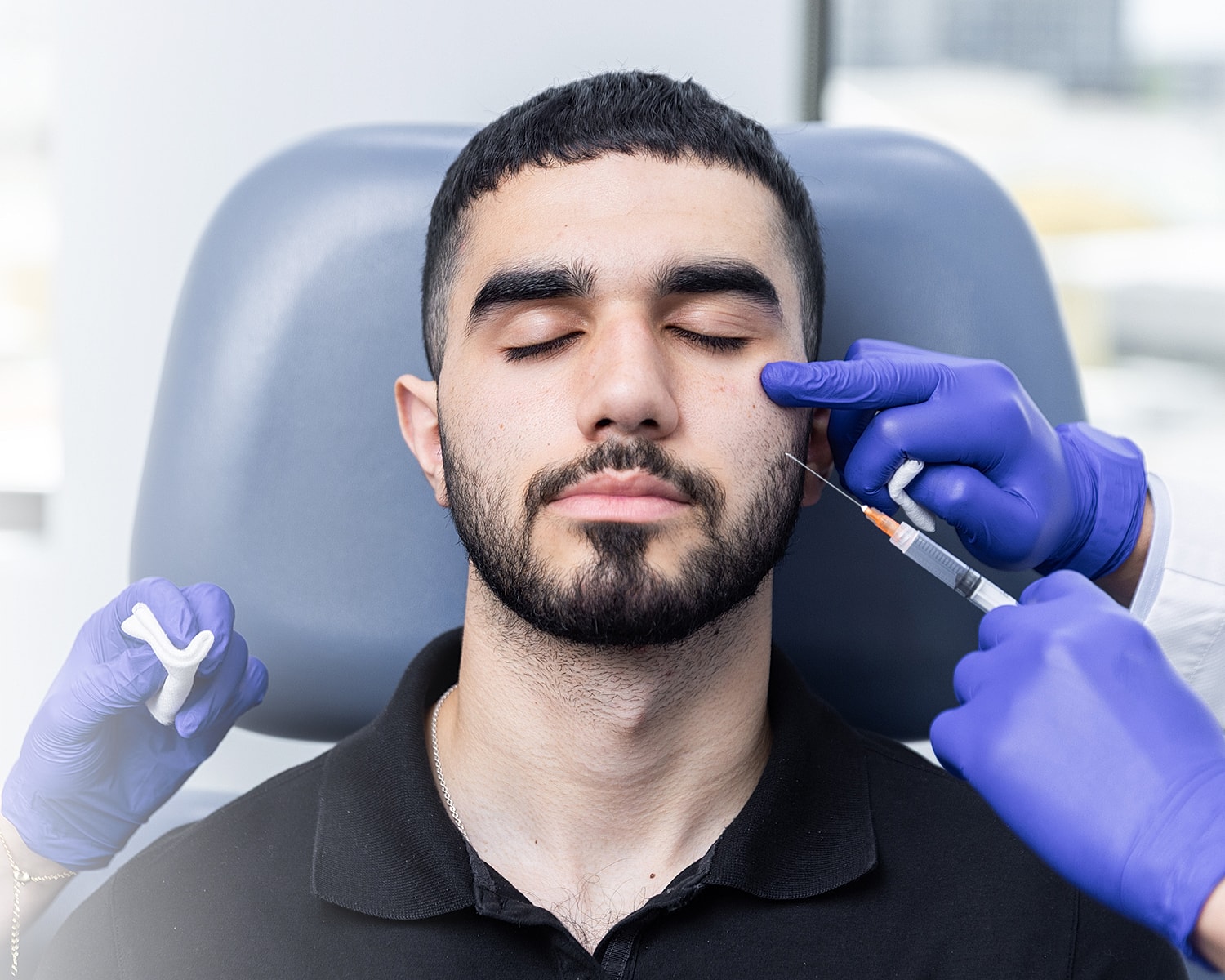 Man receiving facial injection in clinic setting.