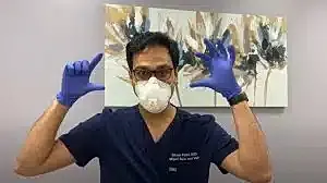 Healthcare professional wearing mask and gloves.