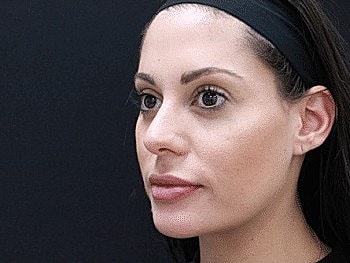 Woman with natural makeup against dark background.