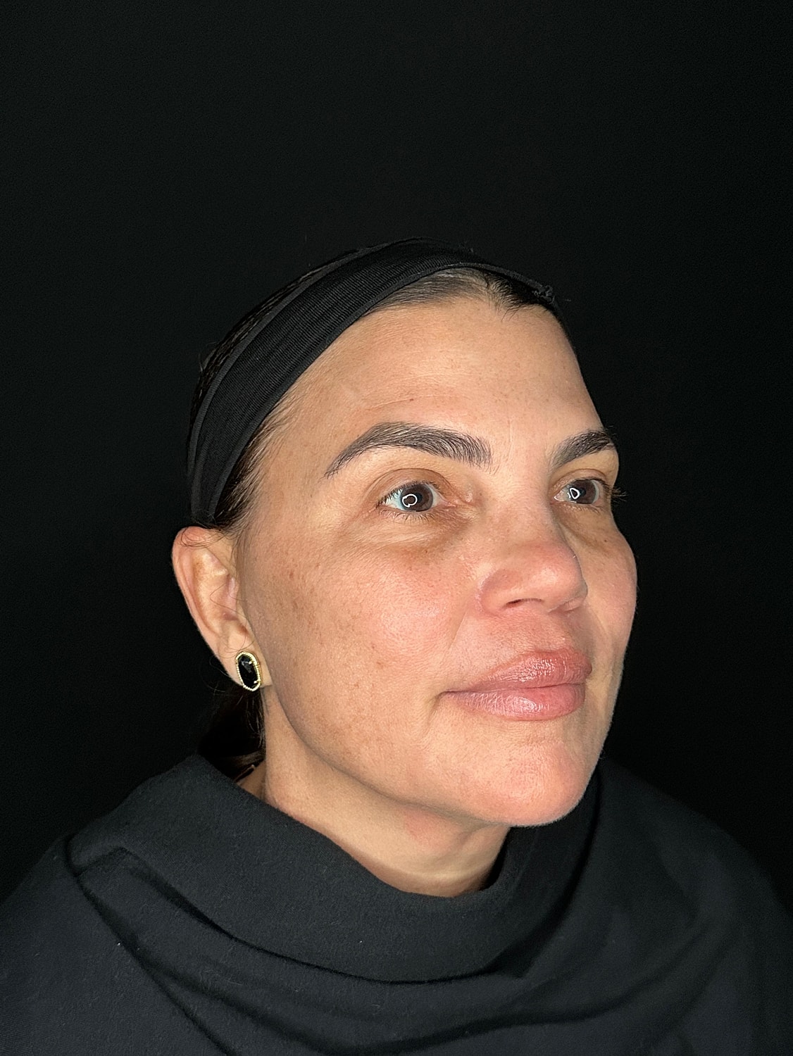 Female portrait with headband against black background.
