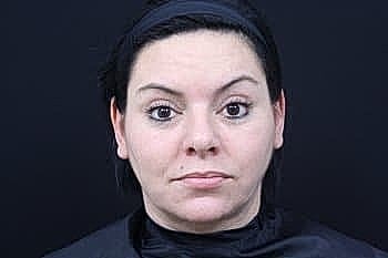 Woman with neutral expression against black background.