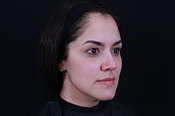 Woman with natural makeup against a dark background.