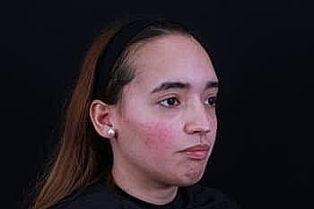 Young woman with long hair, neutral expression.