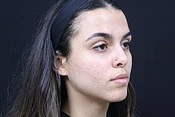 Woman with long hair against black background.