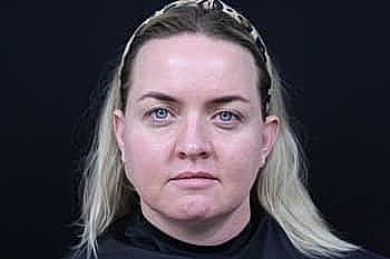 Woman with blonde hair against dark background.