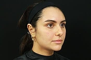 Woman with black headband against dark background.