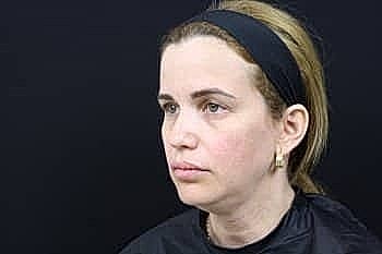 Woman with headband against a dark background.