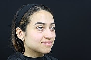 Woman with neutral expression against black background.