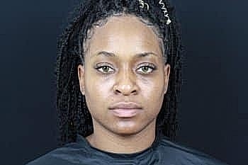 Individual with braids against a dark background.