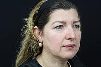 Woman with long hair against a dark background.