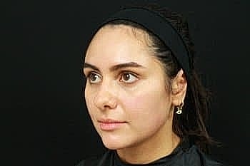 Woman with headband against black background.