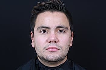 Person with short hair against a dark background.