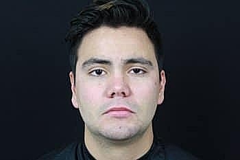 Profile photo of a young man against black background.