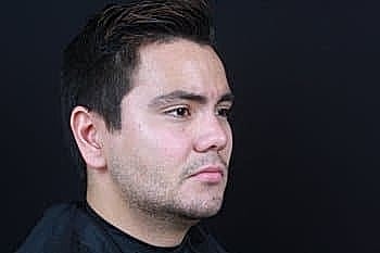 Man with short hair against a dark background.