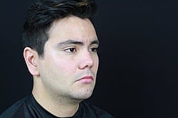 Man with short hair against a black background.