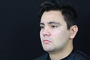 Man with short hair against black background.