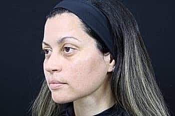 Woman with long hair against black background.