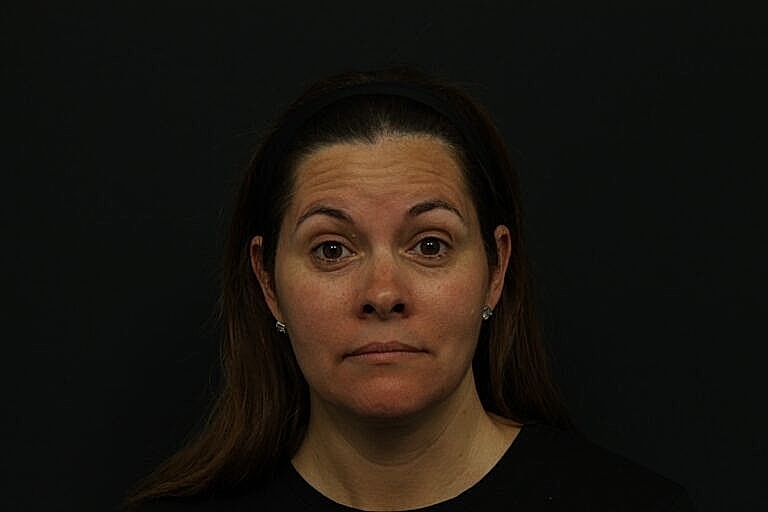 Woman with neutral expression against dark background