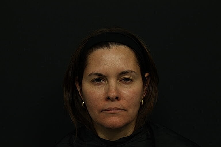 Woman with brown hair against dark background.