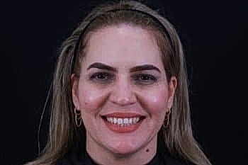 Smiling woman with long hair and hoop earrings.