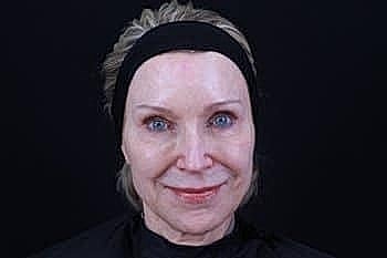 Woman with natural makeup against dark background.