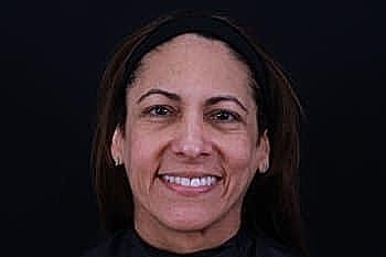 Smiling woman in front of black background.
