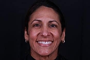 Smiling woman with dark hair and earrings.