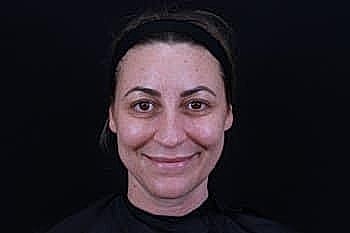 Woman smiling, black backdrop, natural look.