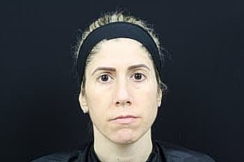 Person with neutral expression against a dark background