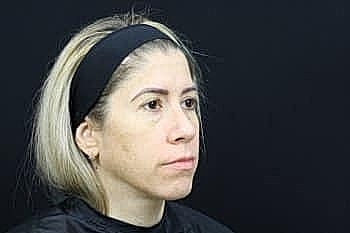 Woman with light hair and headband against black background.