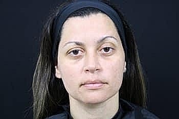 Woman with long hair and neutral expression.