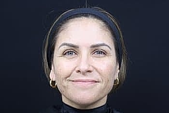 Woman smiling against a dark background.