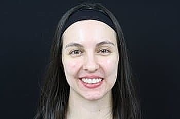 Smiling woman with long hair on black background.