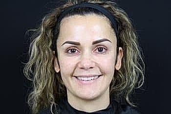 Smiling woman with curly hair and headband.