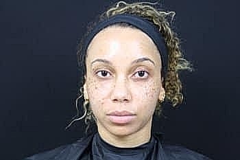 Woman with curly hair in front of black background.