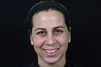 Smiling woman with dark hair against black background.