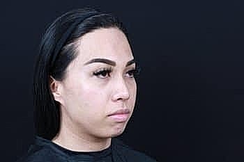 Person with long hair and makeup against black background