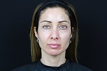 Woman with minimal makeup against black backdrop.