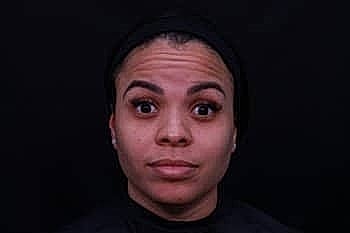 Person with neutral expression against dark background