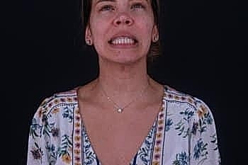 Smiling woman with floral shirt against dark background.
