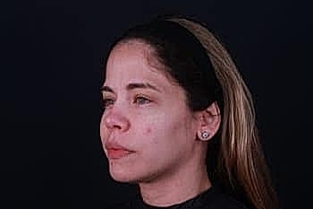 Woman with long hair against black background.