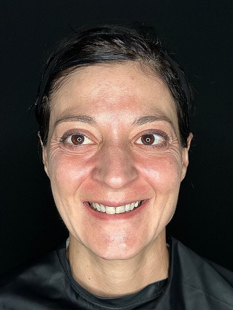 Smiling woman with dark background, close-up portrait.