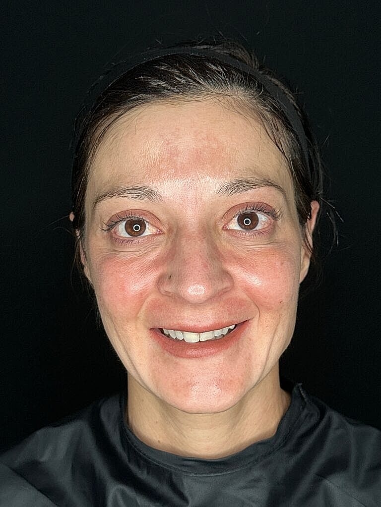 Woman smiling in front of dark background.