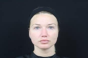 Woman with neutral expression against dark background