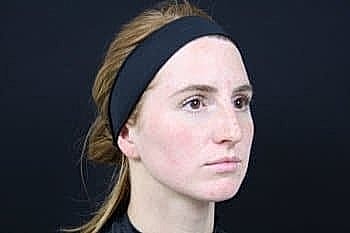 Woman with headband against dark background.