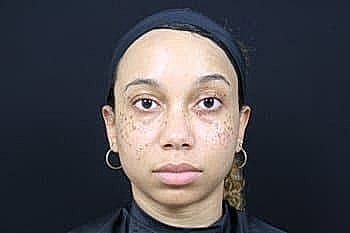 Person with facial markings and a neutral expression.