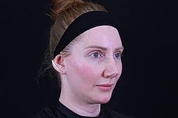 Woman with headband, neutral expression, dark background.